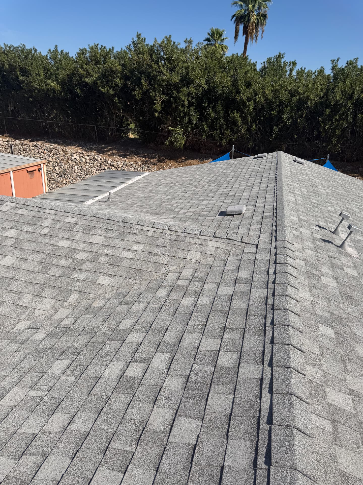 Gray shingle roof with ridge and vents viewed from the rooftop